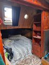 Jonge Jan boat cabin with bed, bookshelf, and porthole windows.